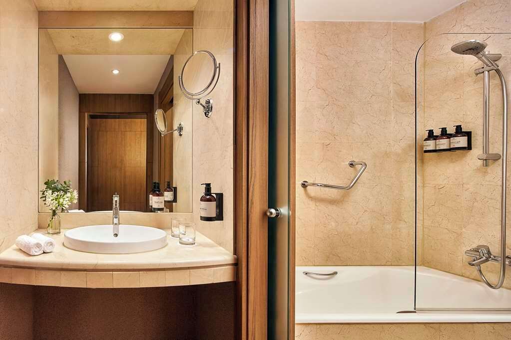 Une salle de bain moderne avec un lavabo rond, un miroir et une douche séparée par une paroi de verre.