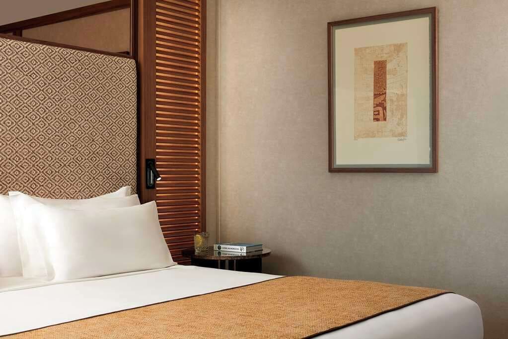 Una habitación de hotel con una cama, un cuadro enmarcado en la pared y un separador con diseño.