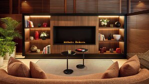Una sala de estar moderna con un televisor de pantalla plana grande, estanterías de madera con objetos decorativos y un área de descanso confortable.