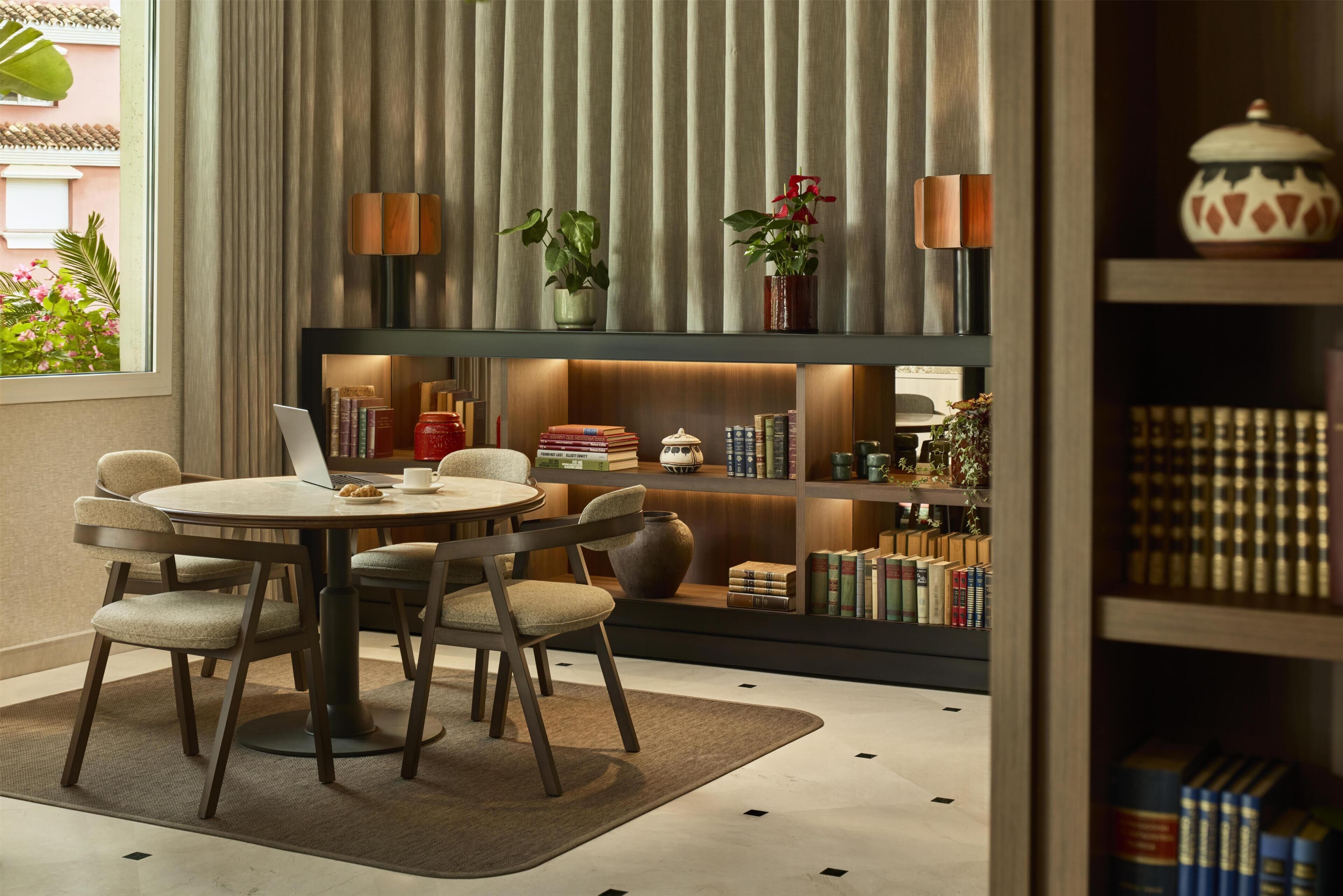 Un espace repas moderne avec une table ronde, des chaises et une bibliothèque contenant des livres et des objets décoratifs.