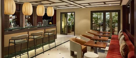 A bar area with stools, a counter with bottles, and a seating area with tables and chairs.