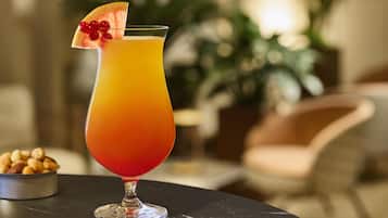 Een cocktailglas met een kleurovergang, versierd met een vrucht en bessen, op een marmeren tafel.