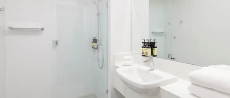 A modern bathroom with a glass-enclosed shower, a white sink, and a large mirror.