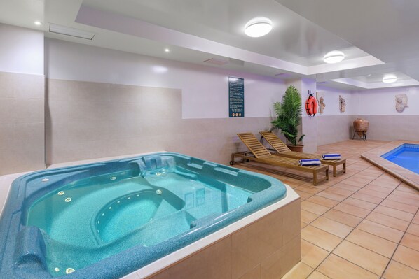 Un área de spa con un jacuzzi, sillones reclinables, una pequeña piscina y un panel informativo.