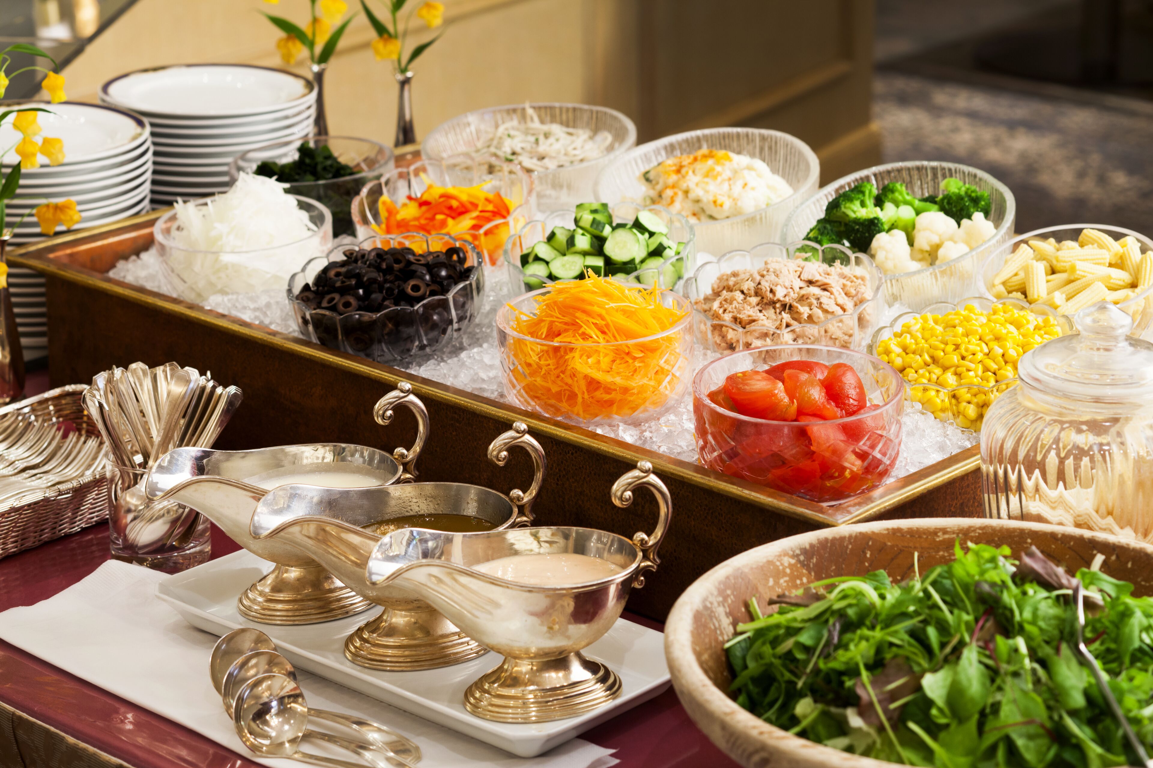 A buffet with various food items and silverware.