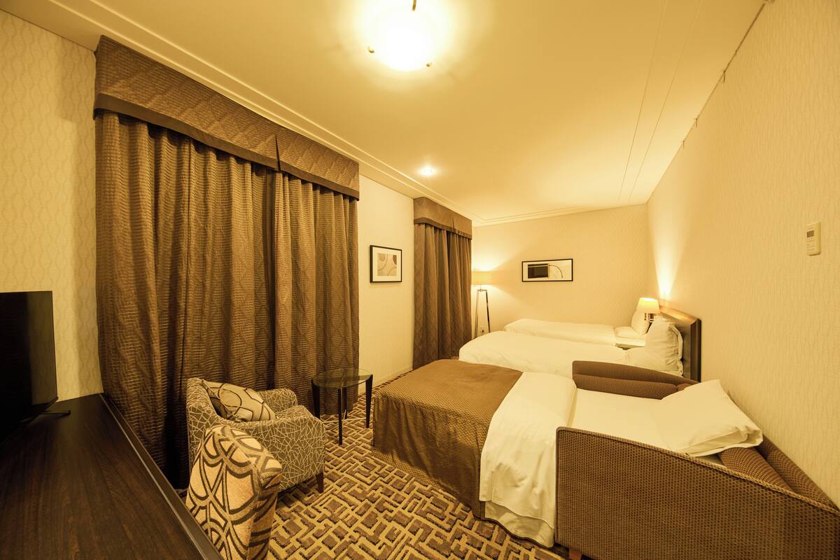 Een hotelkamer met een bed, een bank, een televisie en een lamp.