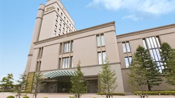 Chiba Hotel features a modern design with a prominent corner tower and flat facade, marked by a covered entrance with a glass canopy.