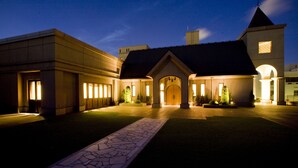 Un hotel con un patio central, una entrada amplia con galería techada y una torre de campanas.