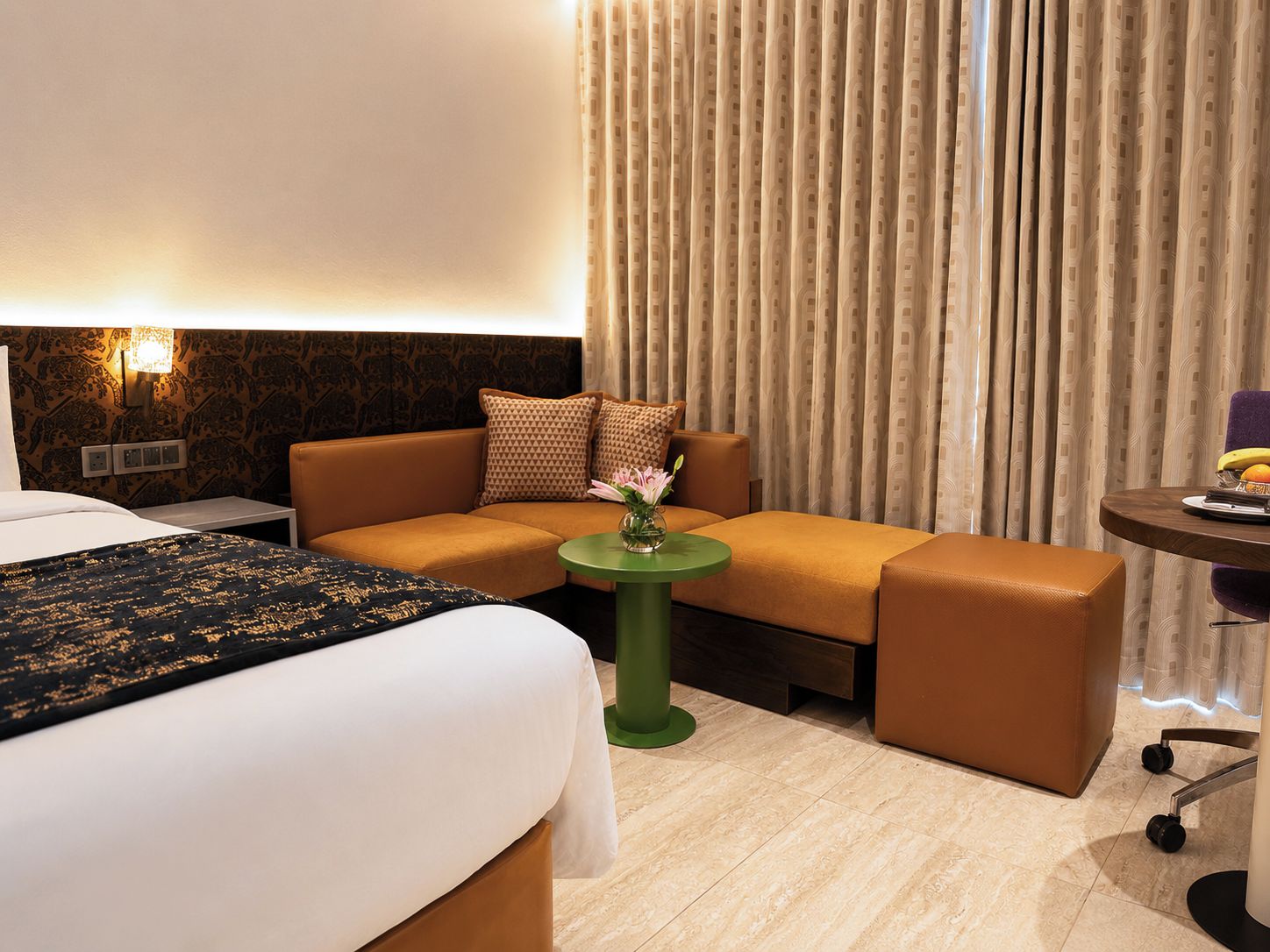 A hotel room with a bed, a sofa, a small table, and a chair.