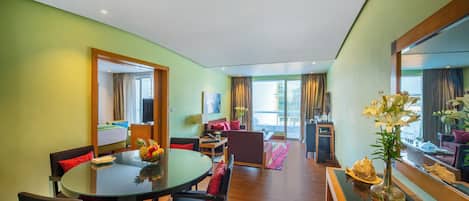 A hotel room with a dining area, a living space, and a large mirror.