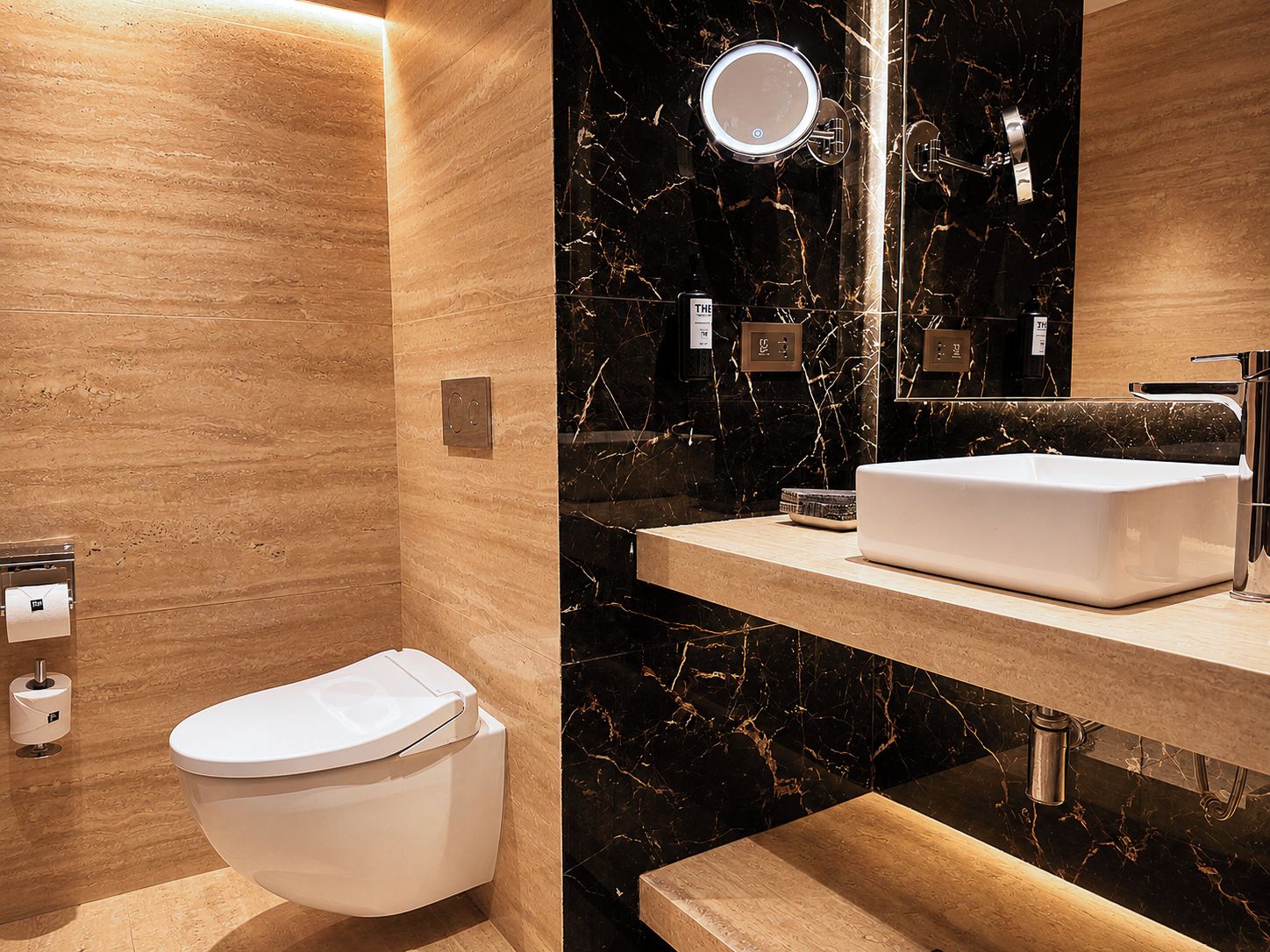 Une salle de bain moderne comprenant des toilettes, un meuble-lavabo avec un évier et un miroir.