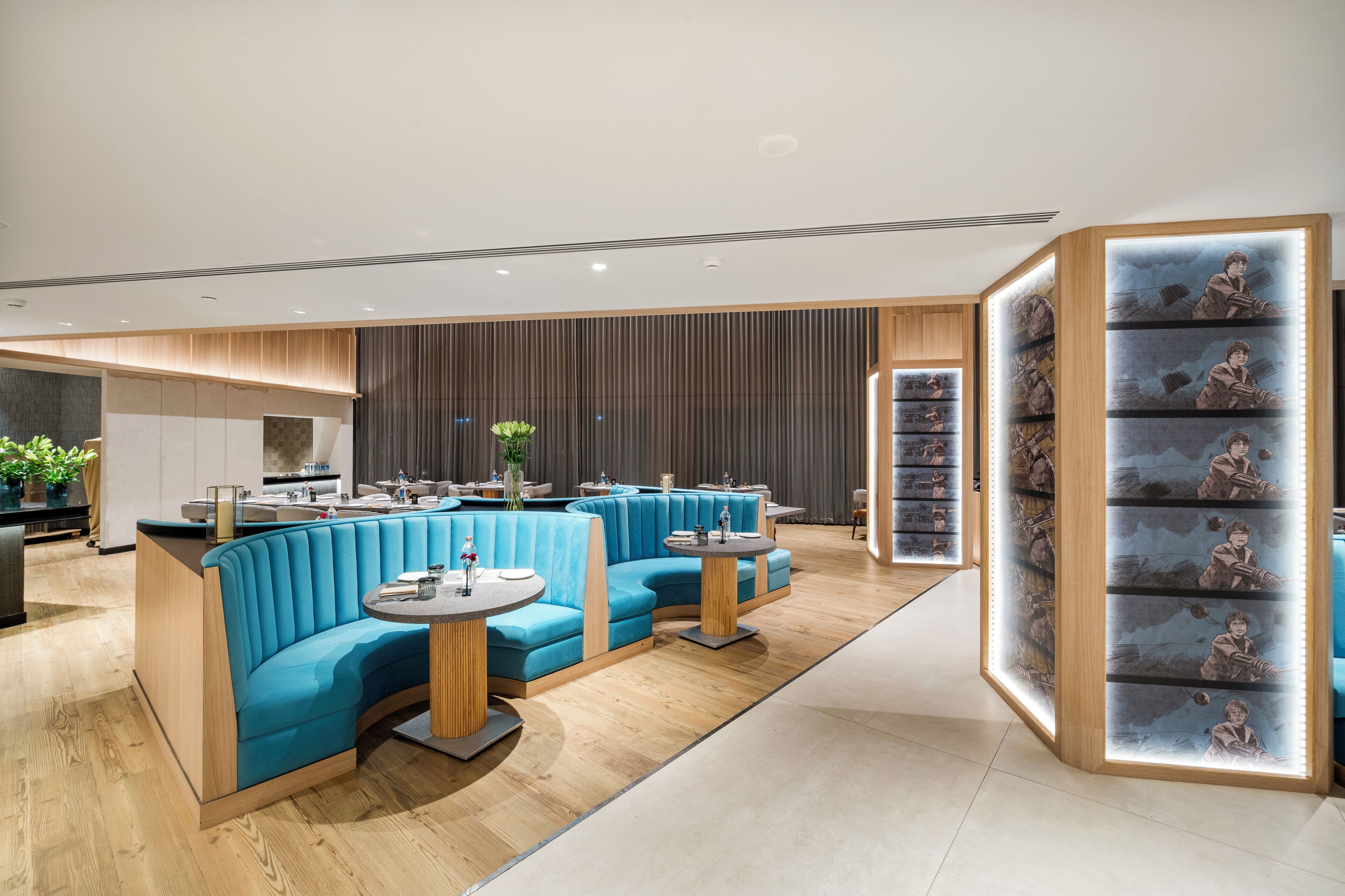 Un interior moderno con zonas de estar en azul, detalles de madera y una exposición de cuadros enmarcados.