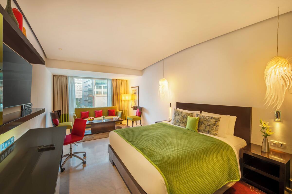 Une chambre d’hôtel avec un grand lit, un bureau, une chaise, un canapé et une télévision.