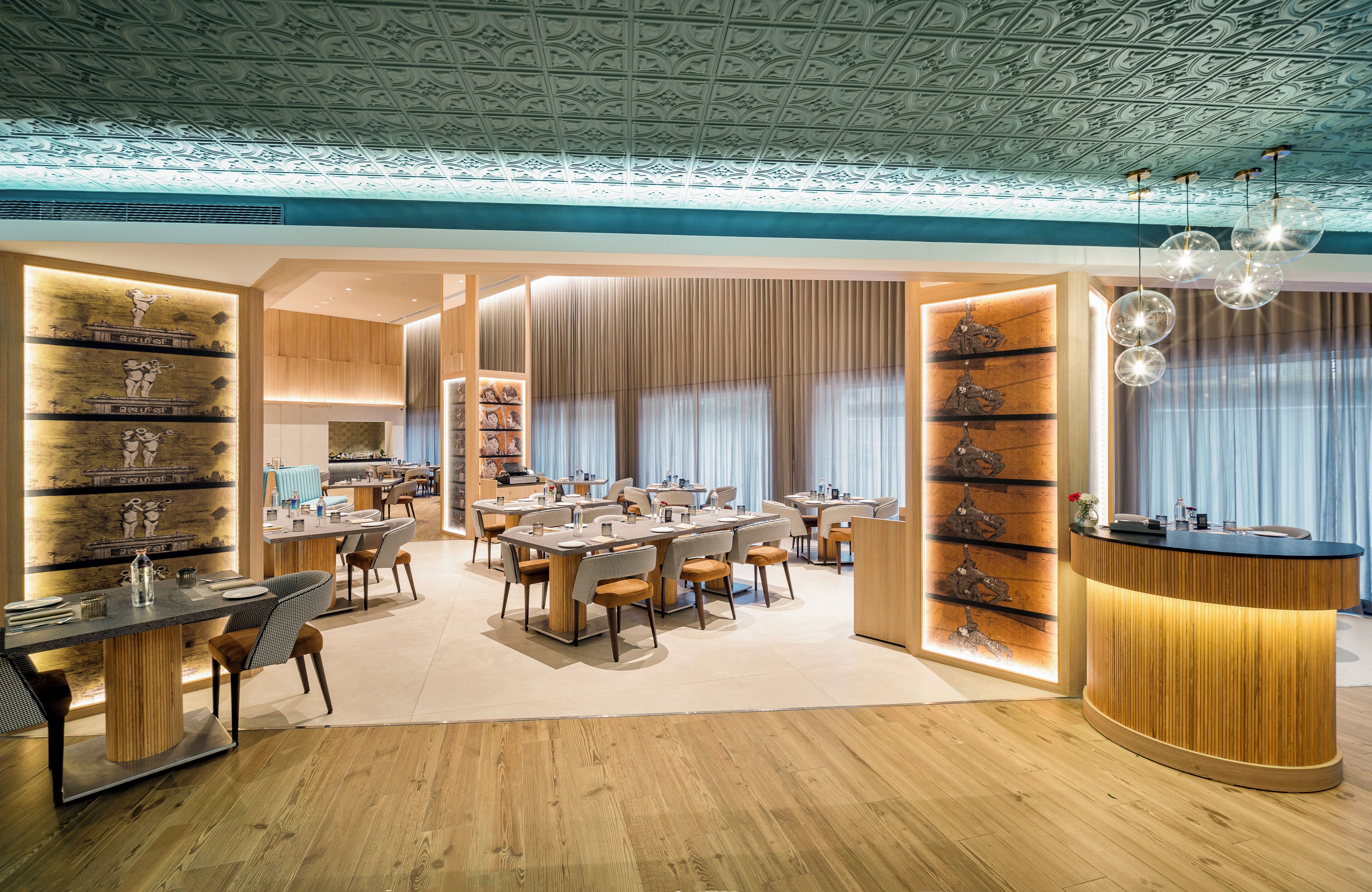 A modern dining area with a central table, surrounded by chairs, and a counter with a wooden finish.