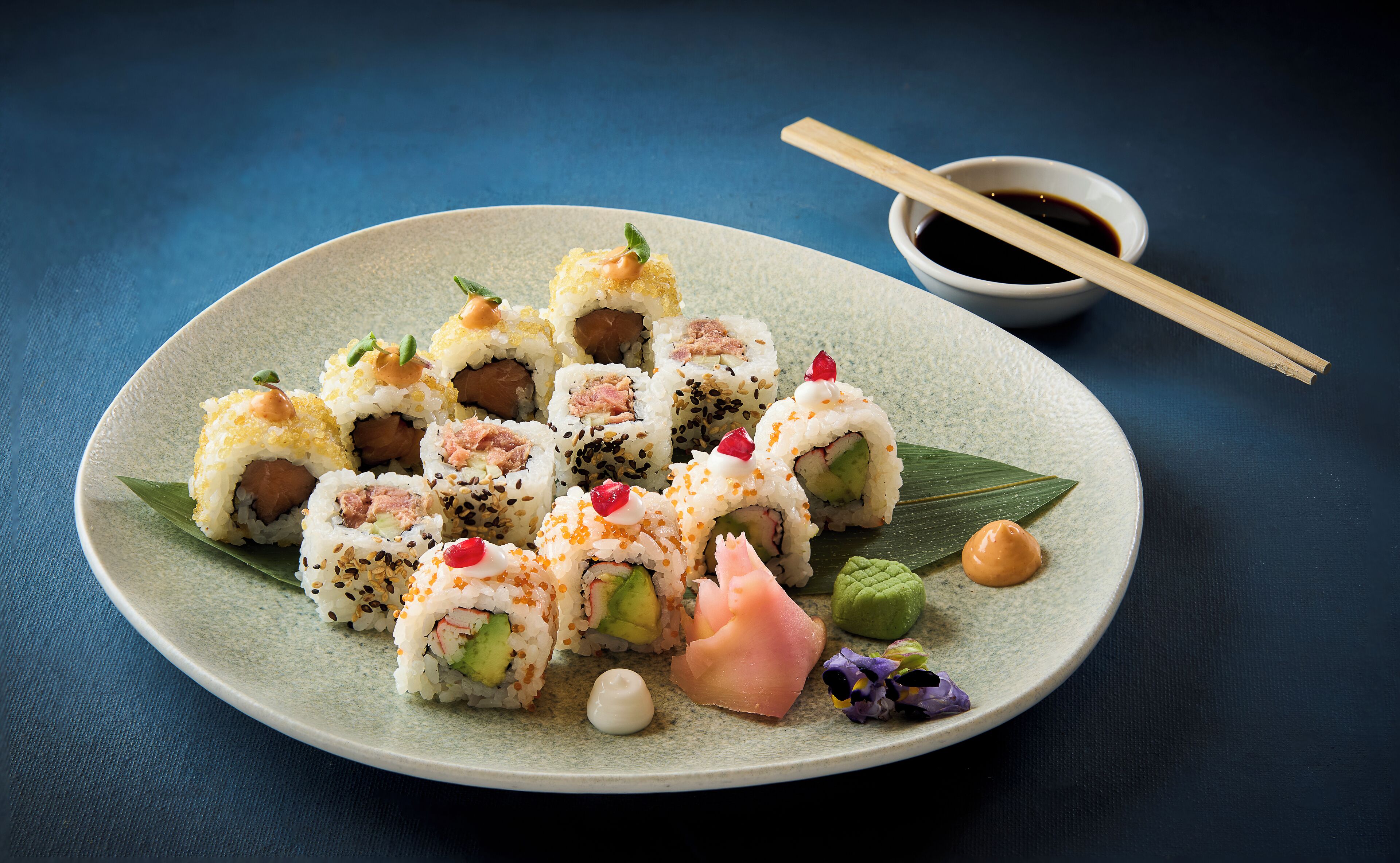 Une assiette de sushis garnis de différentes sortes d’ingrédients et un petit bol de sauce soja.