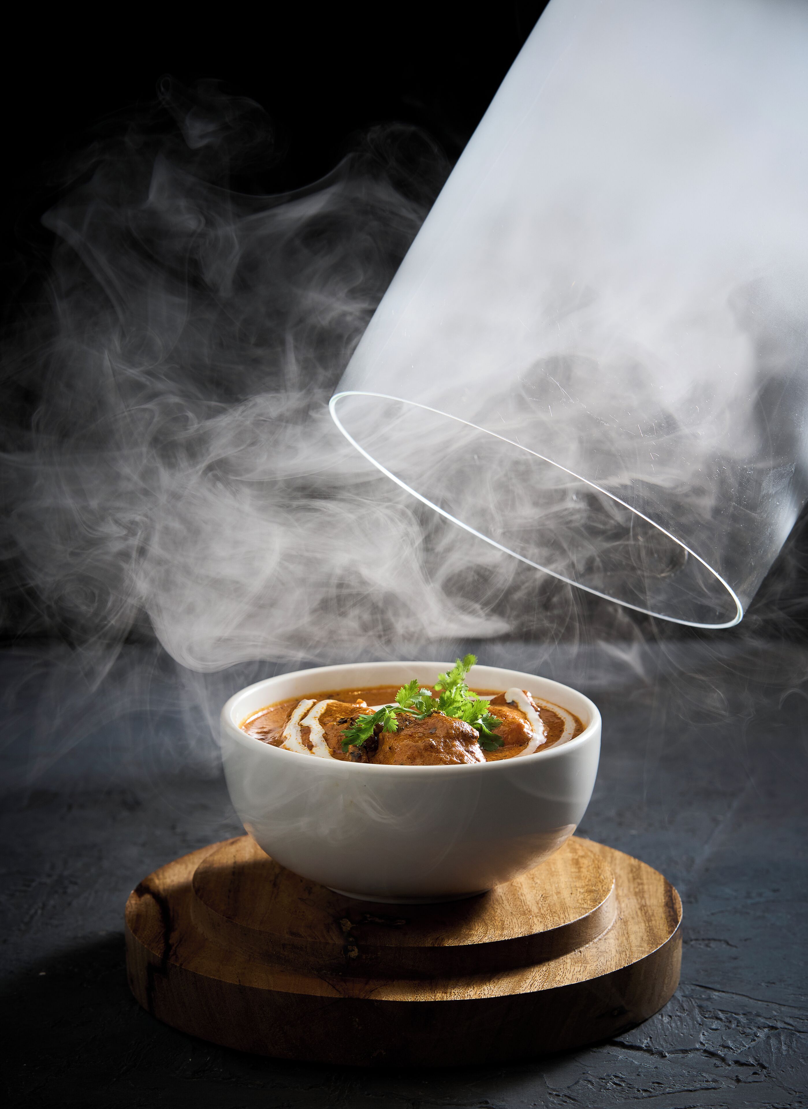 Un plato de comida con vapor saliendo, sobre una tabla de madera.