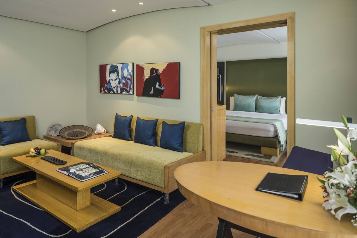Une chambre d’hôtel avec un canapé, une petite table, un lit et des œuvres d’art accrochées au mur.