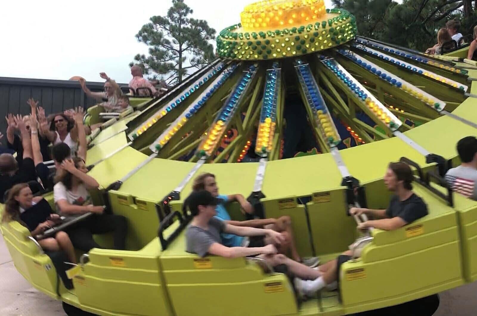 A green amusement ride with multiple seats and a central rotating structure.