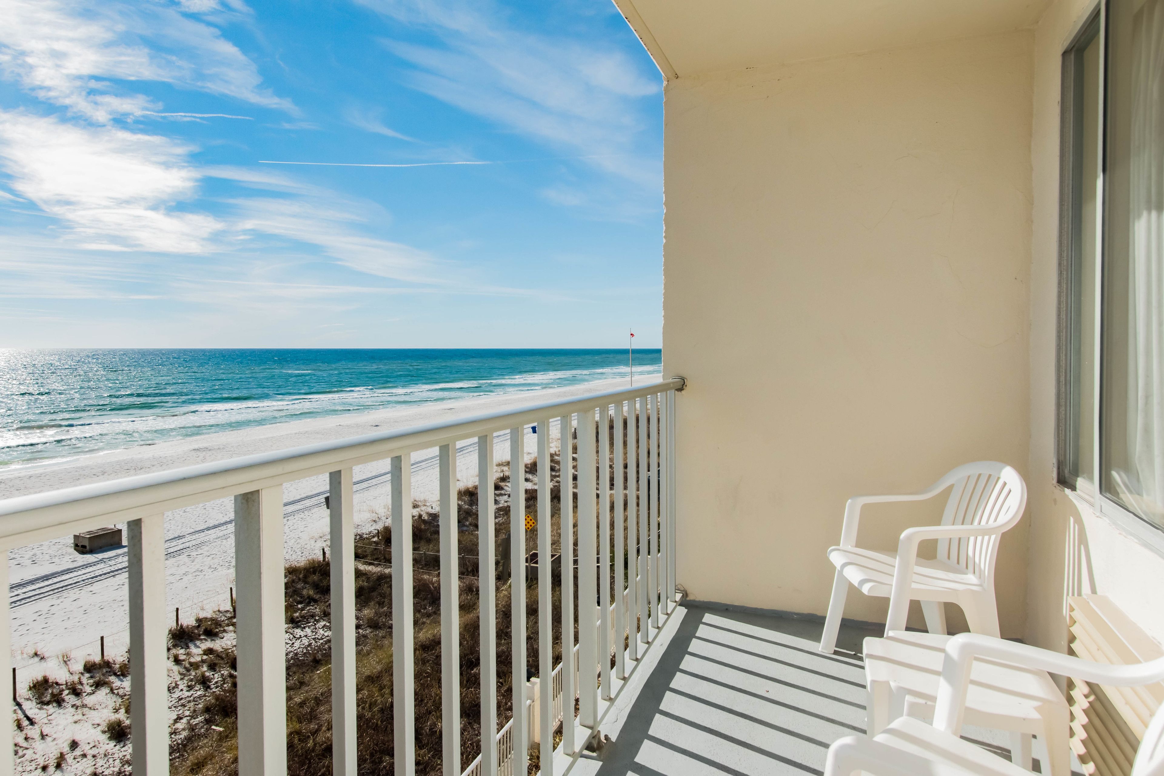 A balcony with a view of the beach and ocean.