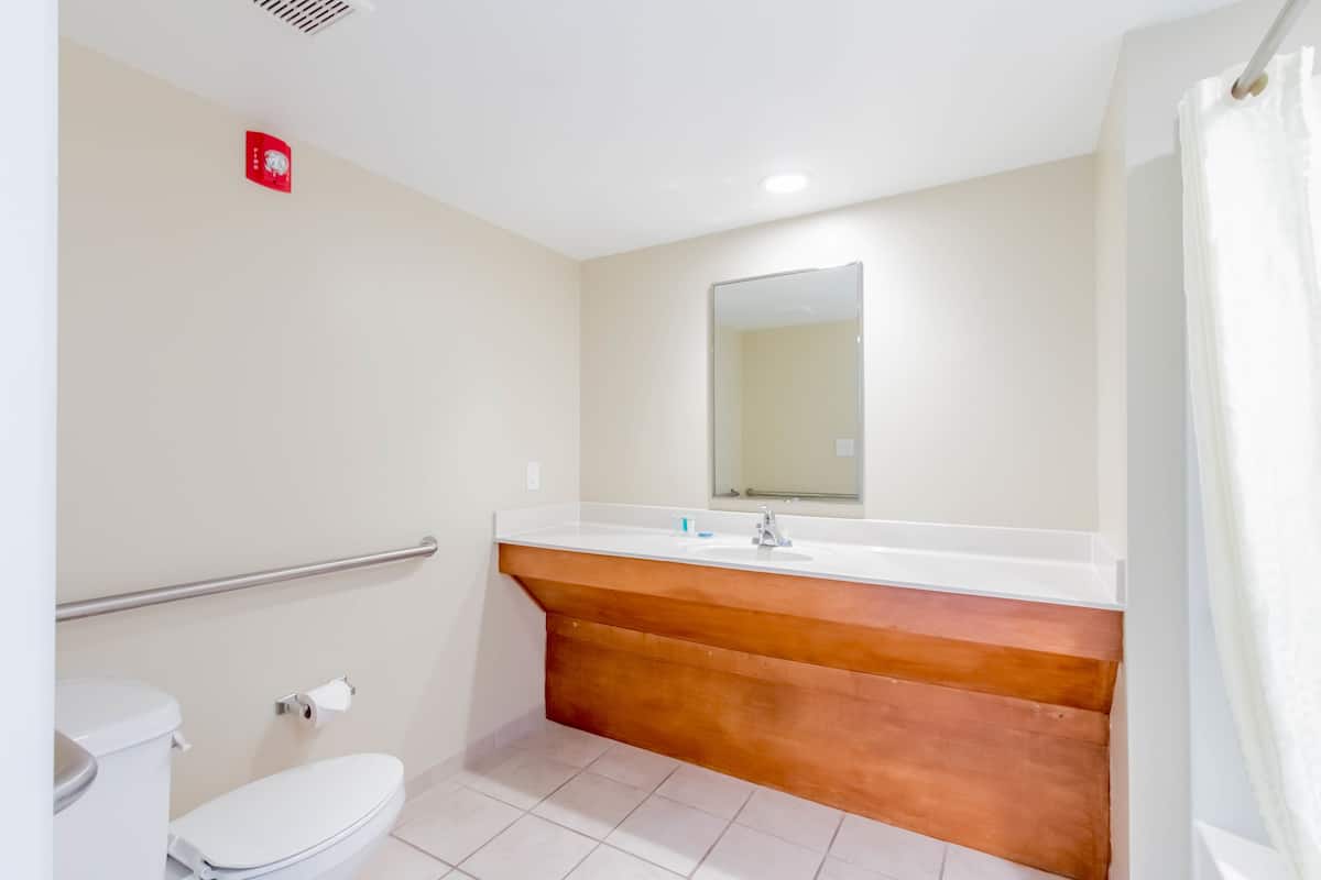 A bathroom with a white toilet, a sink with a mirror above it, and a shower curtain.