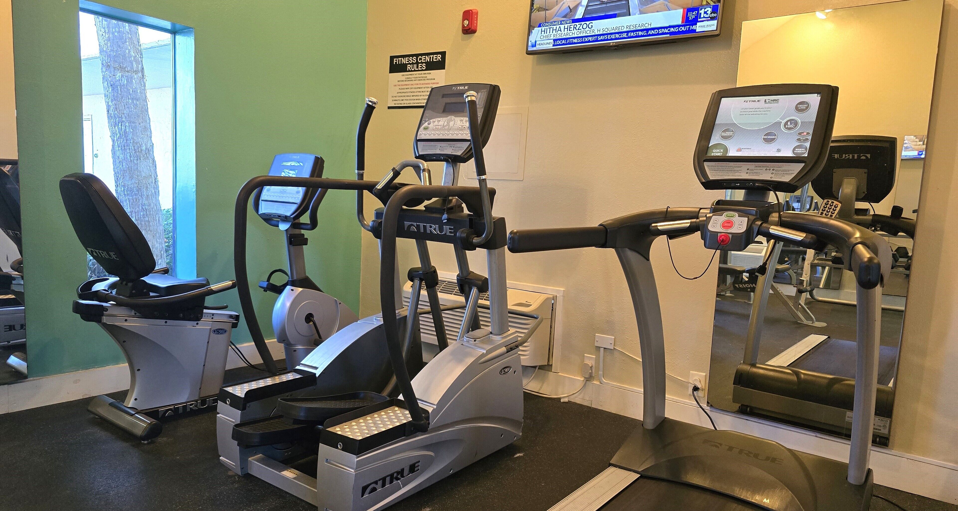 Un gimnasio equipado con diversas máquinas de ejercicio, incluyendo cintas de correr y elípticas.