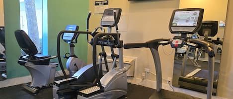 Un gimnasio equipado con diversas máquinas de ejercicio, incluyendo cintas de correr y elípticas.
