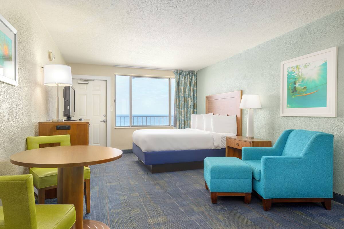 A hotel room with a bed, a desk, a chair, a round table, and a window.