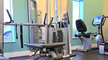 A gym with various exercise equipment, including a bench press, a cable machine, and a stationary bike.