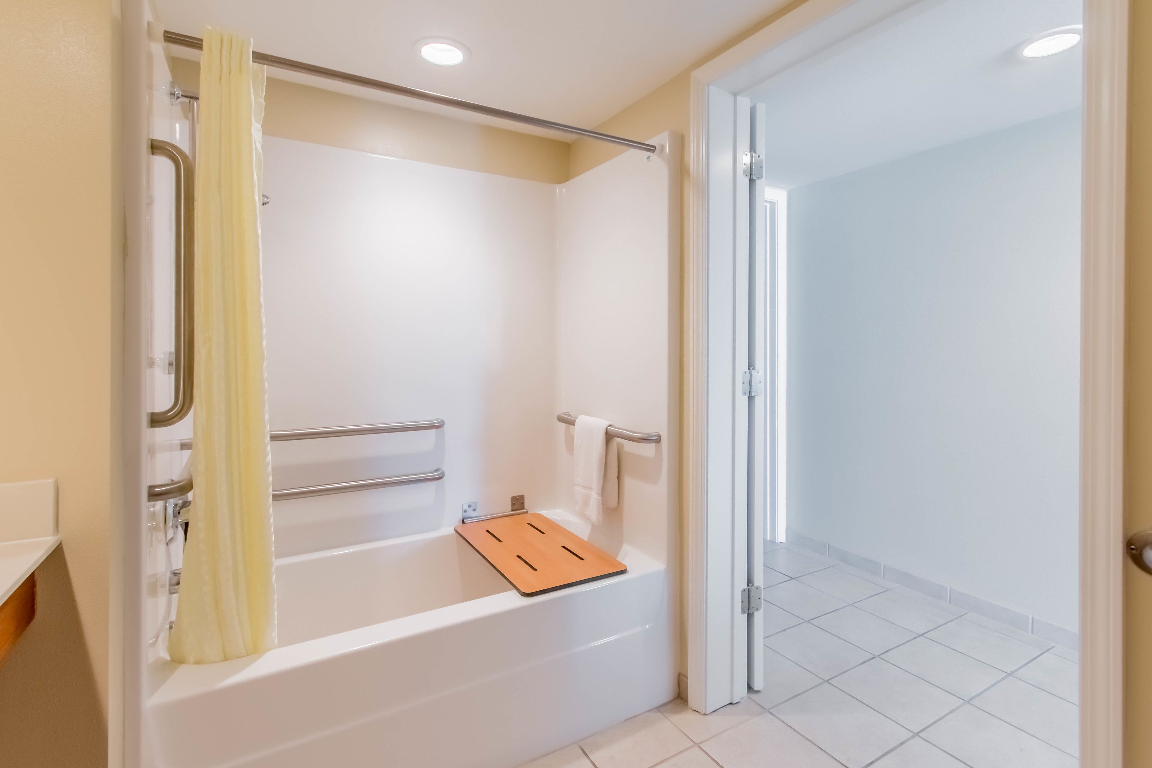 Une salle de bain moderne équipée d’une baignoire, d’un espace douche et d’une porte donnant sur une autre pièce.