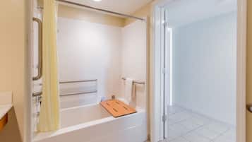 Un baño moderno con bañera, zona de ducha y puerta que da a otra habitación.