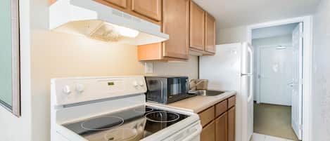 A compact kitchen with a stove, microwave, and refrigerator.