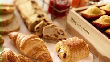 Verschiedene Backwaren, darunter Croissants und Brot, mit einem Schild, auf dem 'ibis kitchen' steht.