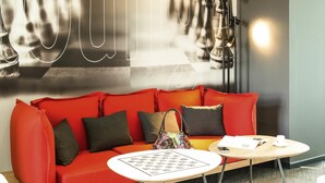 Un moderno vestíbulo de hotel con un sofá rojo, una mesita redonda y una pared con un letrero de neón.