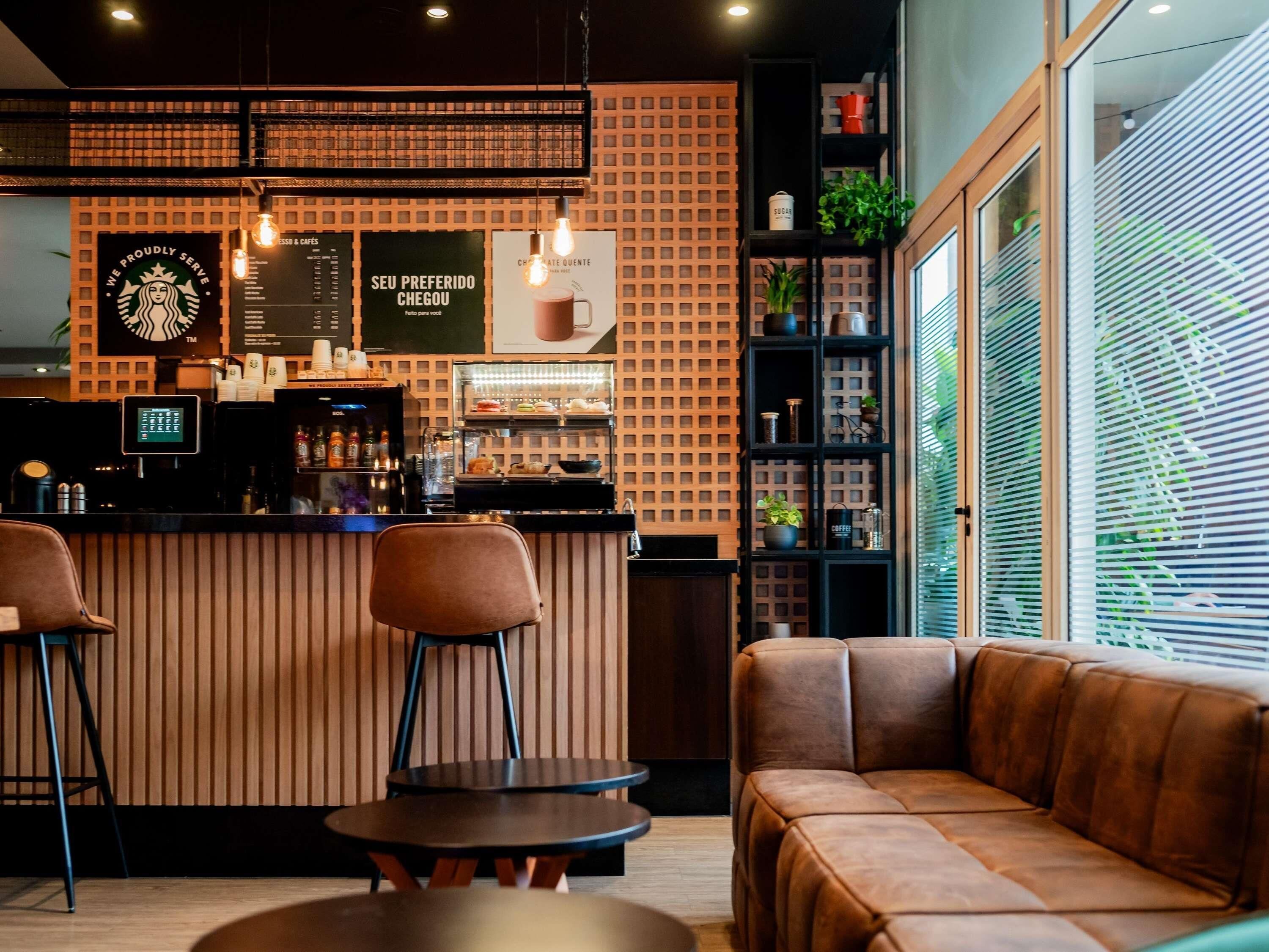 Interior moderno de una cafetería, con mostrador, zona de estar y panel de menú.