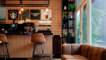Interior moderno de una cafetería, con mostrador, zona de estar y panel de menú.