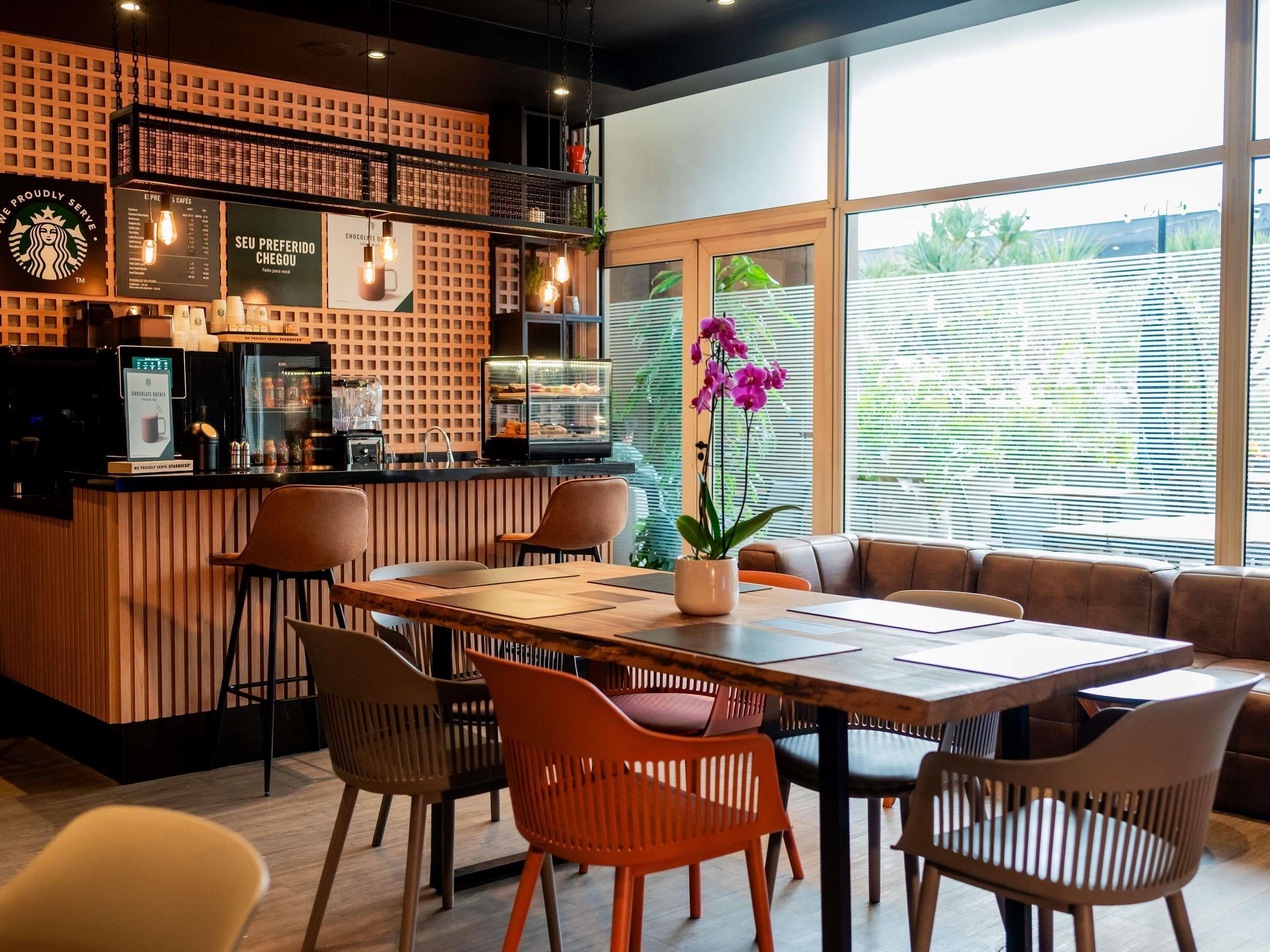Ein modernes Café mit Holztresen, Sitzbereich und großen Fenstern.