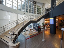Un vestíbulo espacioso con una escalera central, una recepción y una zona de estar con sillones cómodos y una cinta roja.
