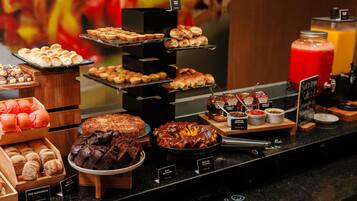 A buffet with various baked goods, including bread, pastries, and desserts.