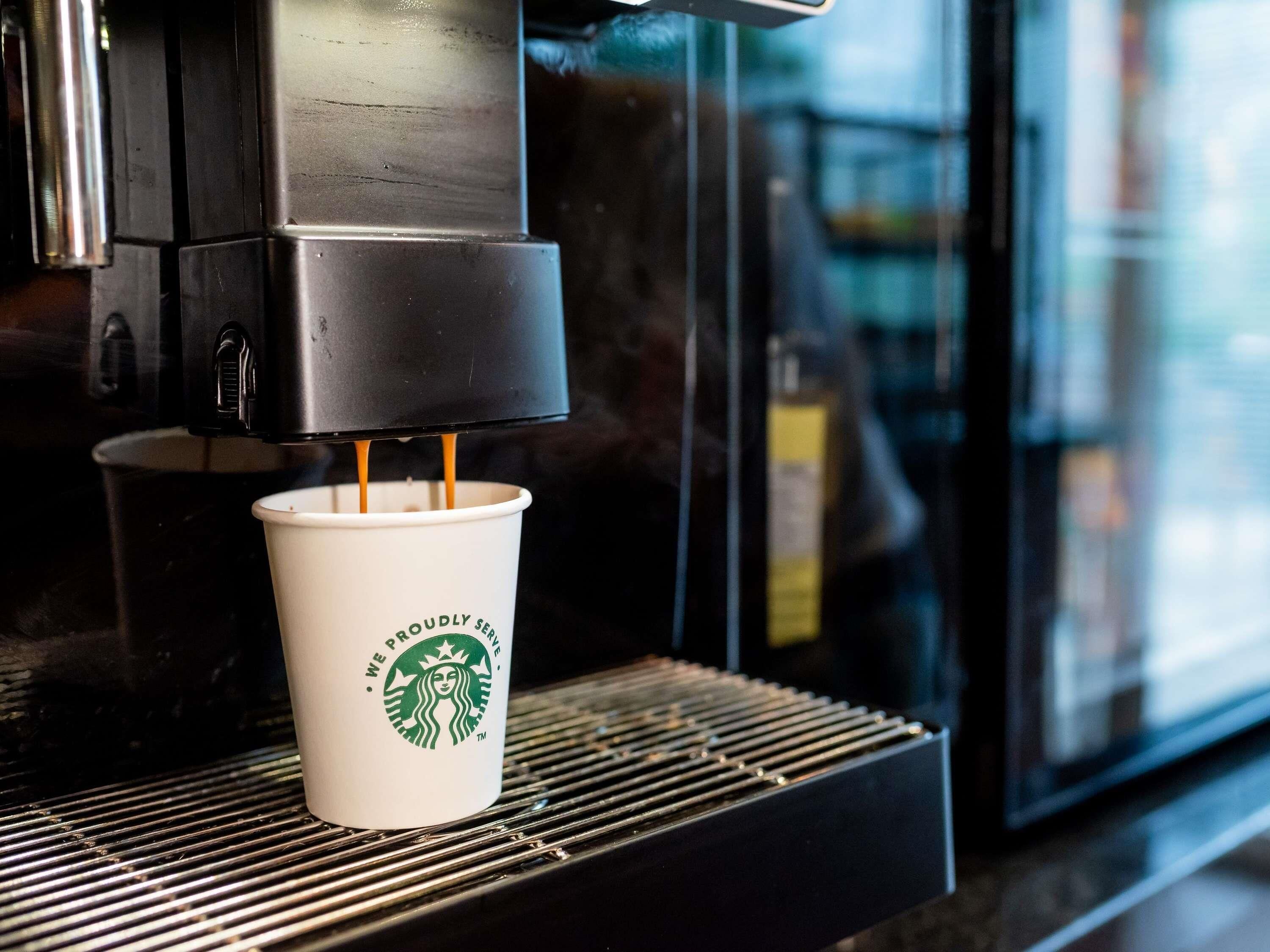 Una máquina de café sirviendo café en un vaso Starbucks.