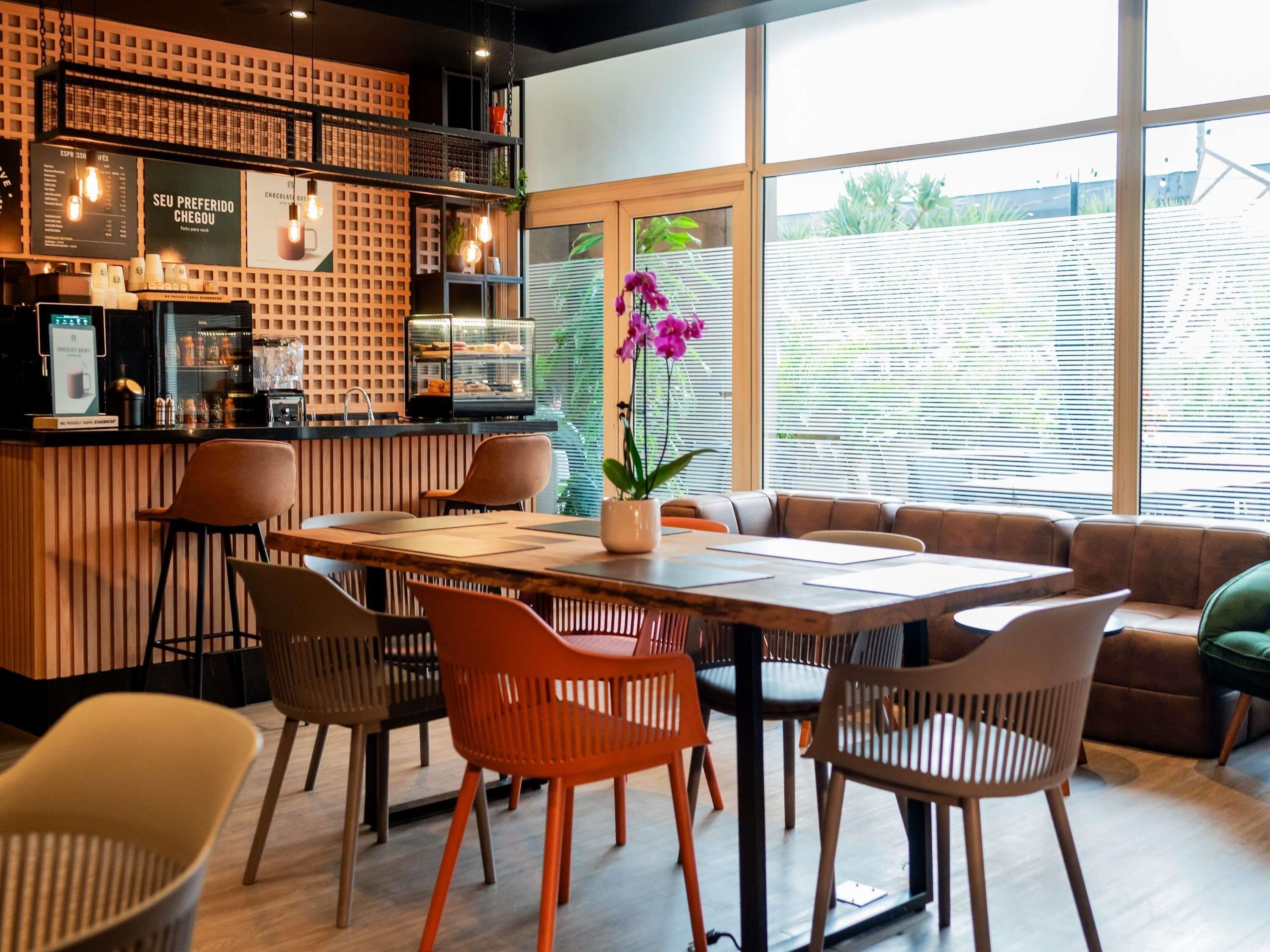 Un café moderno con mostrador de madera, zona de estar y ventanas amplias.