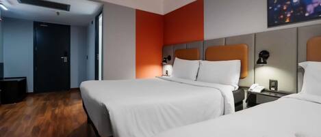 A hotel room with two beds, a flat-screen TV, a desk with a lamp, and a painting on the wall.