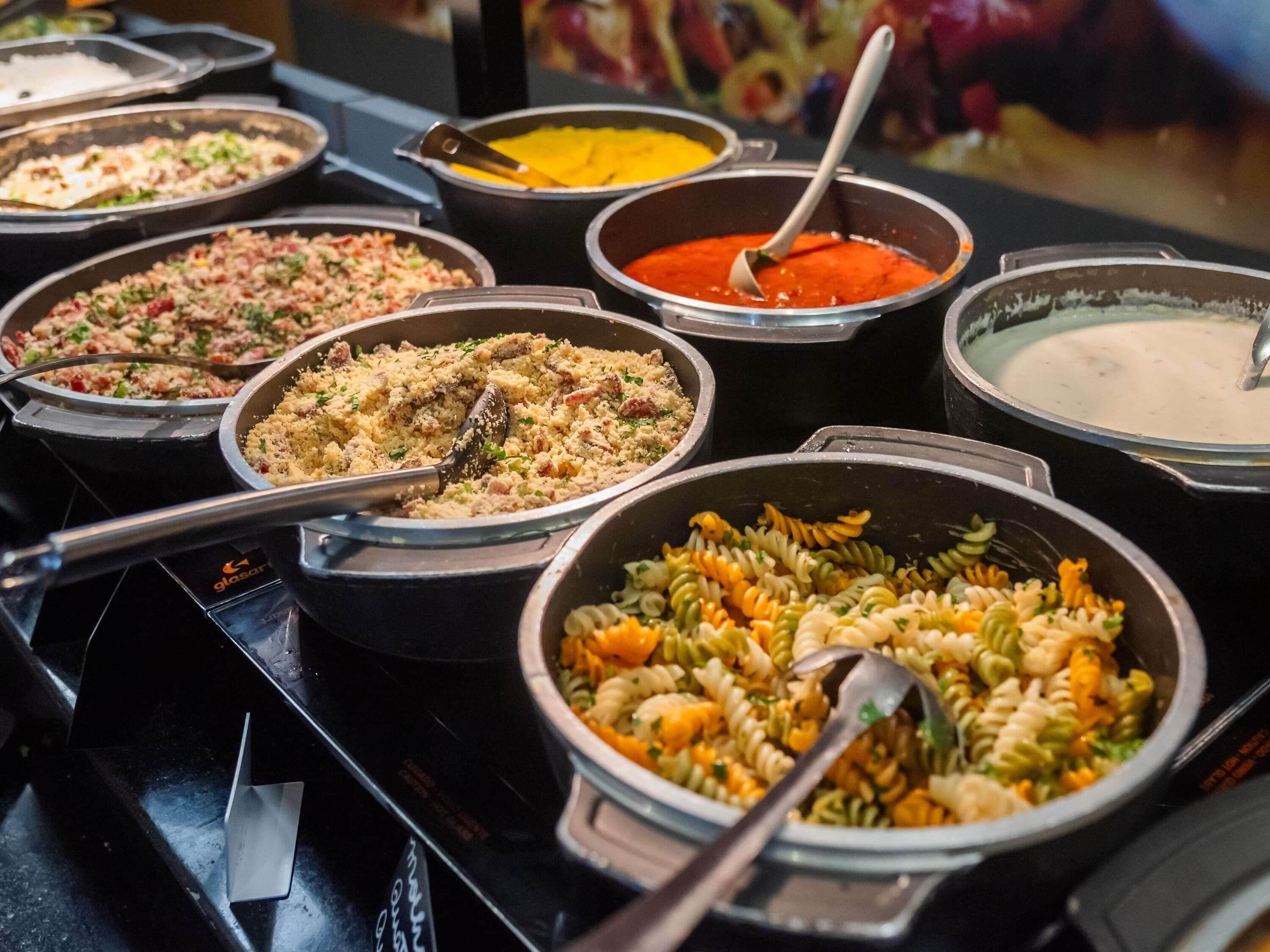 A buffet with various dishes including pasta, rice, and soups.