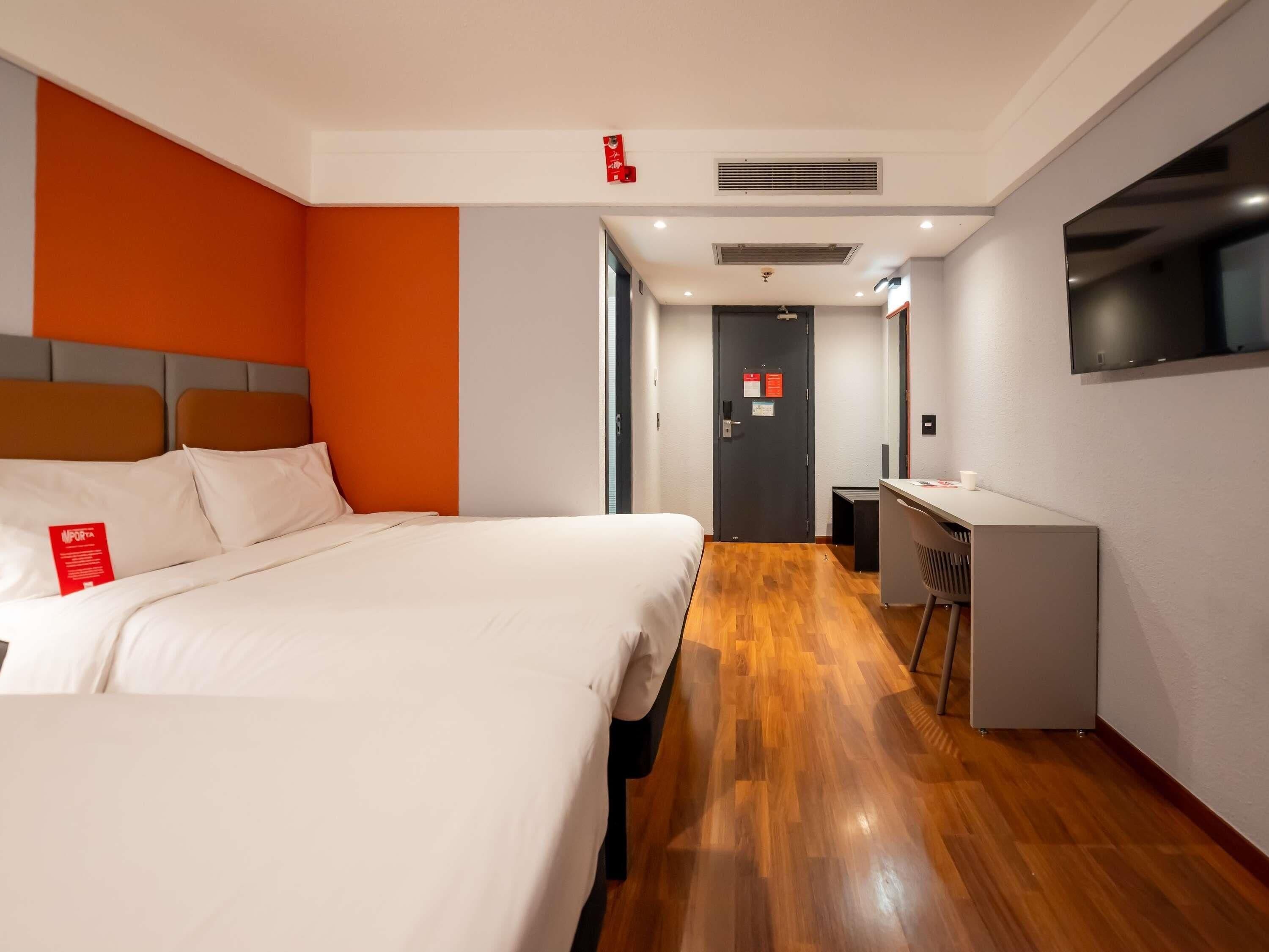 A hotel room with a bed, desk, and a TV.