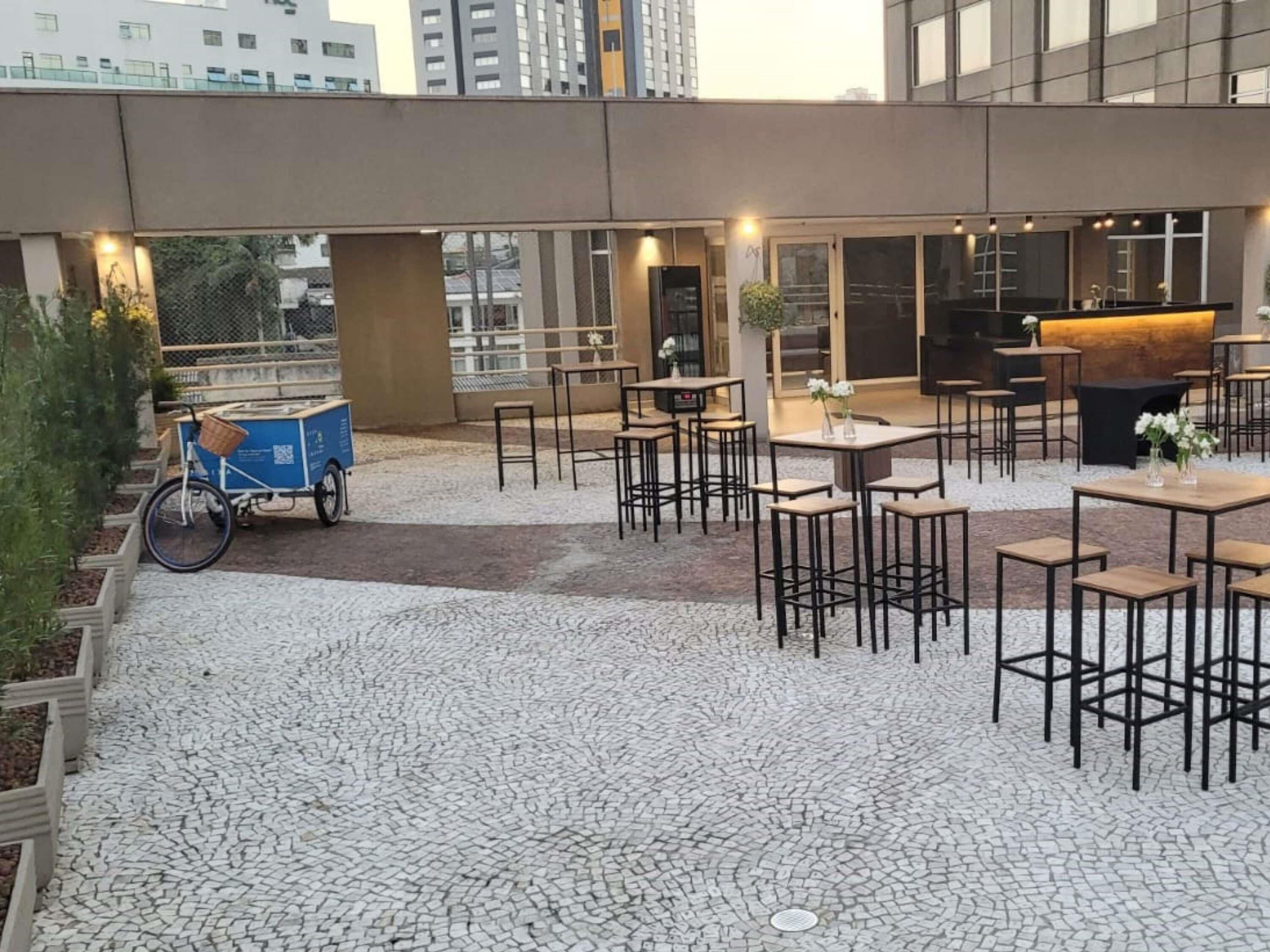An outdoor seating area with tables and chairs, a bicycle cart, and a piano.