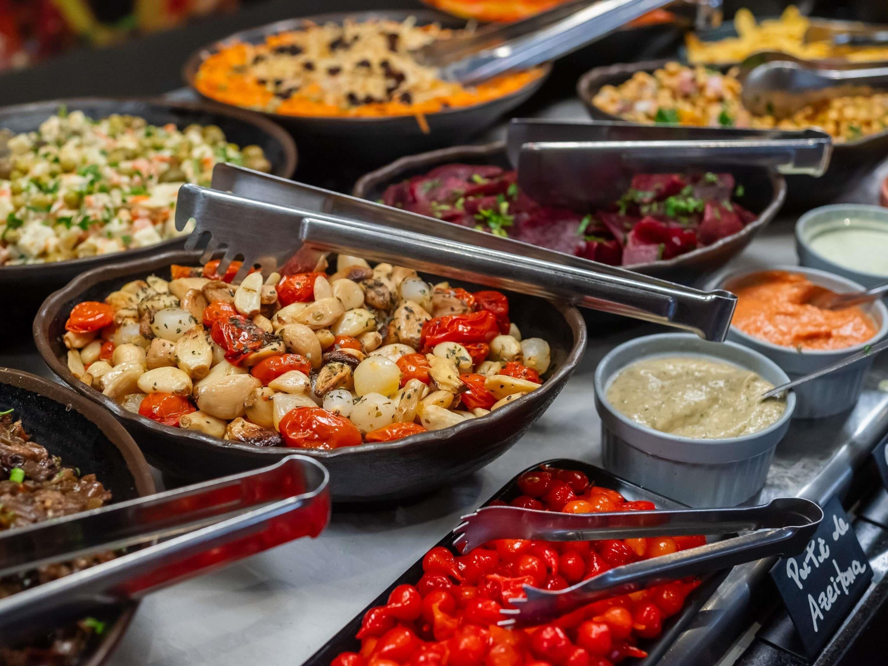 A buffet with various dishes, including roasted vegetables and dips.