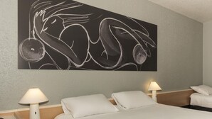 Une chambre d’hôtel comprenant un lit, deux lampes de chevet, une œuvre d’art accrochée au mur et une table de chevet avec une lampe.