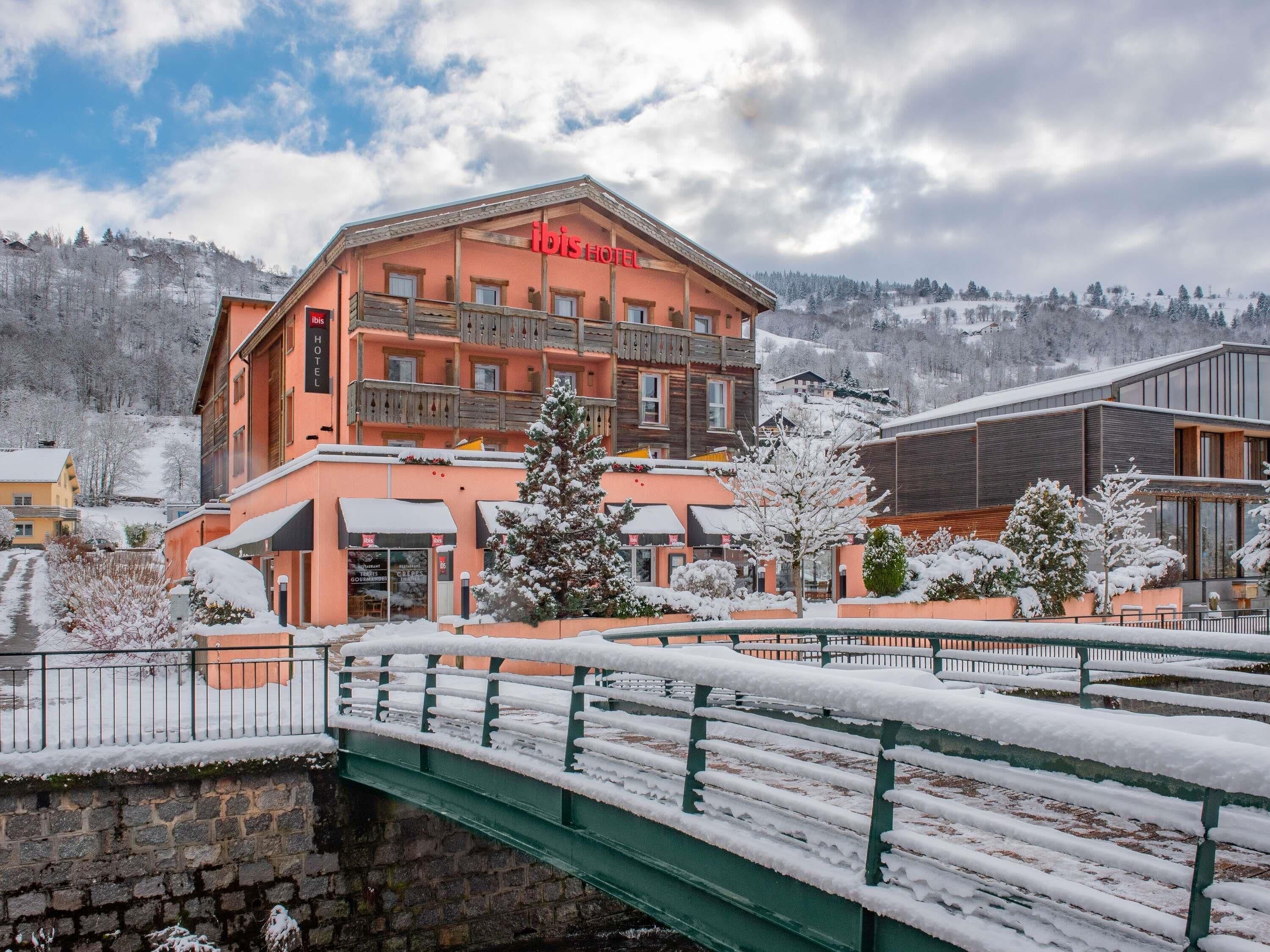 Un hôtel doté d’un balcon, d’un pont et entouré d’un paysage enneigé.
