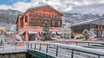 Un hôtel doté d’un balcon, d’un pont et entouré d’un paysage enneigé.