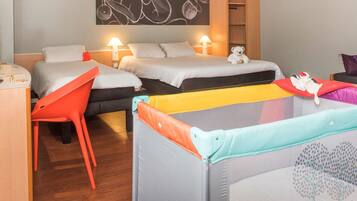 Two beds with white bedding, a wardrobe, and a table with a lamp, perfect for families.