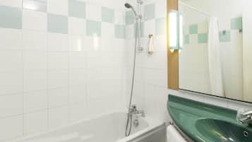 A bathroom with a white bathtub, a green sink, and a mirror above the sink.